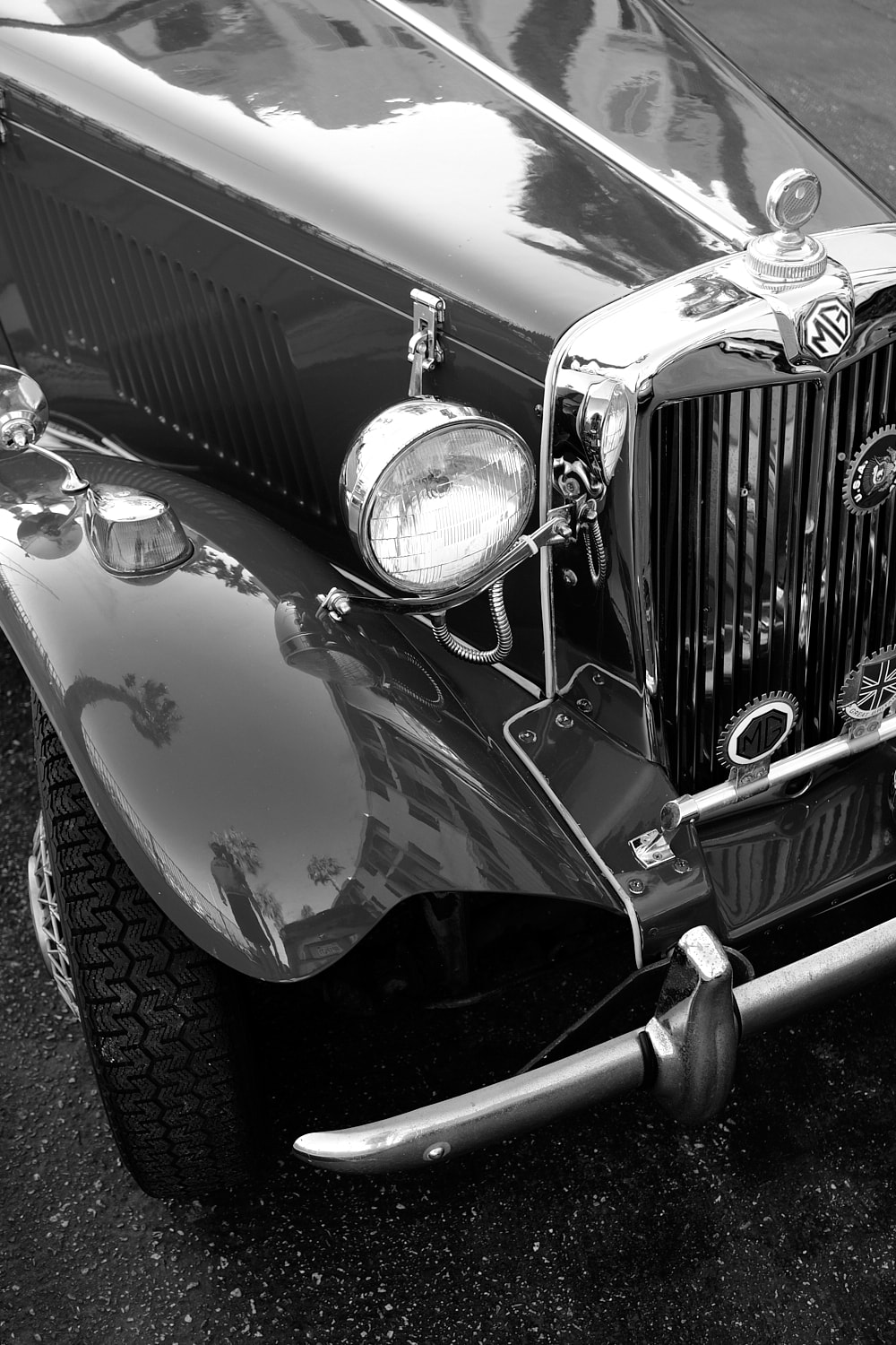 Black and white portrait photo of a close up of the grill and hood of an old MG sports car.